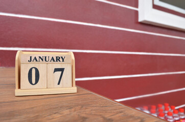 January 7, Number cube with wooden table beside the wall.