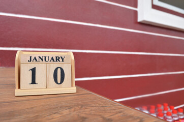 January 10, Number cube with wooden table beside the wall.