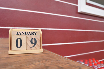 January 9, Number cube with wooden table beside the wall.