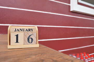 January 16, Number cube with wooden table beside the wall.