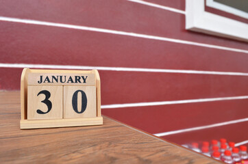 January 30, Number cube with wooden table beside the wall.