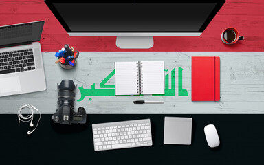 Iraq flag background with headphone,camera, notebook and mouse on national office desk table.Top view with copy space.Flat Lay.