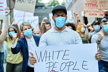 Black man with protective face mask participating in demonstrations against racism.
