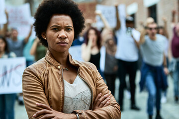 Portrait of displeased black woman with crossed arms on a protest for human rights. - obrazy, fototapety, plakaty