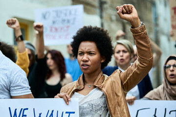 African American woman with raised fist participating in a protest for human rights. - obrazy, fototapety, plakaty