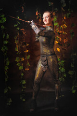 Valkyrie girl in shiny military armor and with a spear in a dark room with plants and vines. Model...