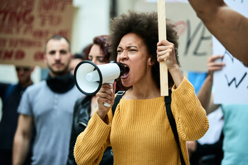 Black female activist shouting through megaphone on a protest.