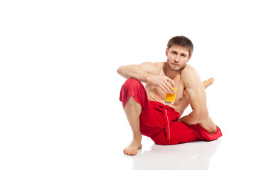 Fototapeta premium Yoga man doing exercises and holding glass with orange juice in studio at white background 