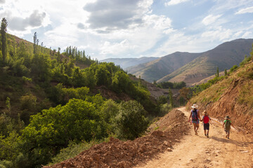 Mother and her kids walking on a mountain trail. Family travel nature trips. Travel tourism adventure concept.