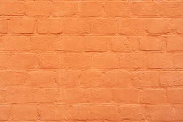 Brick wall is painted with orange paint. Abstract architectural background.