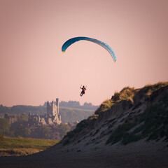 Paragliding on a beach with a castle on the background.