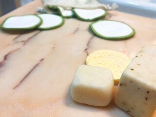 Cosmética belleza natural, ecológica, vegana y reutilizable. Algodones orgánicos, esponja y pastilla de jabón para limpieza facial y corporal. Fondo blanco y madera.