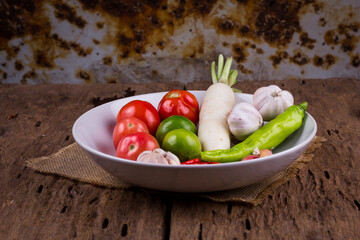 Fresh vegetables on a plate placed on a wooden table.