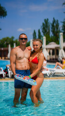 Young beautiful woman and athletic man in a swimsuits in water park