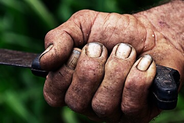 Closeup shot of an old farmers dirty hand gripping a tool handle