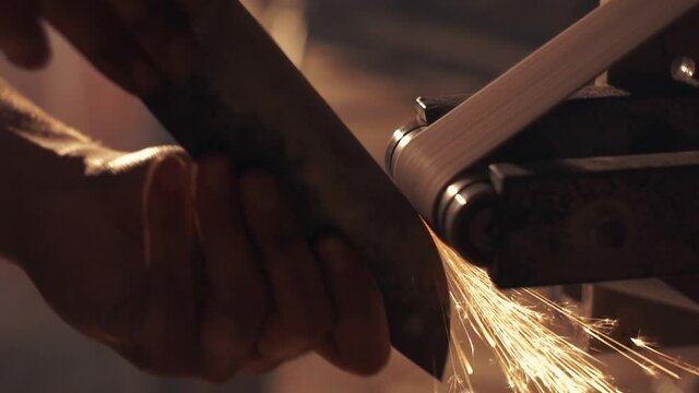 Man sharpening knife with sparks. Work on a sharpening machine.