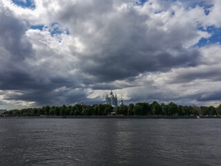 panoramic view of Smolny Cathedral in Saint Petersburg across the Neva river against a dramatic cloudy sky