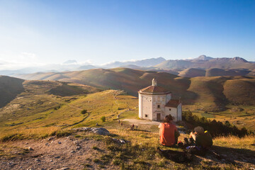 People looking sunset. Mountain ancient ruins at sunset. Medieval ruins of Rocca Calascio church...