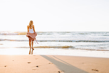 A young slim girl stands walking on the beach or ocean and look at the horizont. A woman dressed in a warm sweater. Toned.