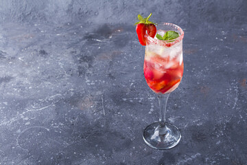 Cooling Rossini italian alcoholic cocktail with sparkling wine, strawberry, ice cubes in champagne glass. Refreshing summer lemonade or ice tea decorated with mint leaves