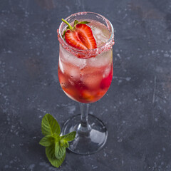 Cooling Rossini italian alcoholic cocktail with sparkling wine, strawberry, ice cubes in champagne glass. Refreshing summer lemonade or ice tea decorated with mint leaves