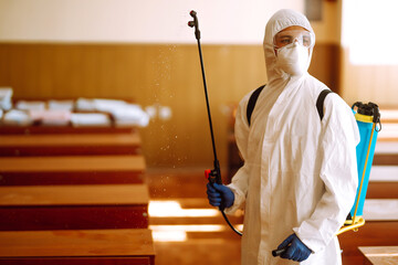 Man in protective hazmat suit with spray chemicals to preventing the spread of coronavirus,...