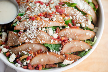 Pear Salad. Classic American or French restaurant salad made with kale, Arugula, almonds, blueberries, walnuts, tomatoes, bacon, blue cheese, avocado, tossed with olive oil.