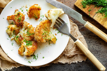 Cauliflower fried breaded with dill on a white plate