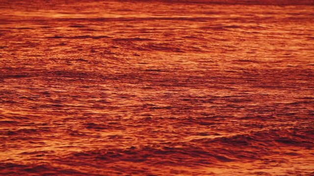 Bright orange, red pacific ocean from reflection of gorgeous Maui Hawaii sunset. 