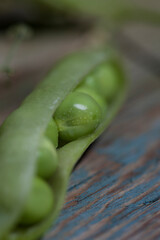 on a wooden background lies fresh green peas with stems and leaves