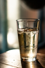 glass of water on a wooden table with backlight from the sun