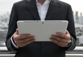 Businessman using digital tablet against view of the city