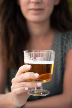Beautiful brown woman in a green dress holding a glass of beer. Selective focus. Close up.
