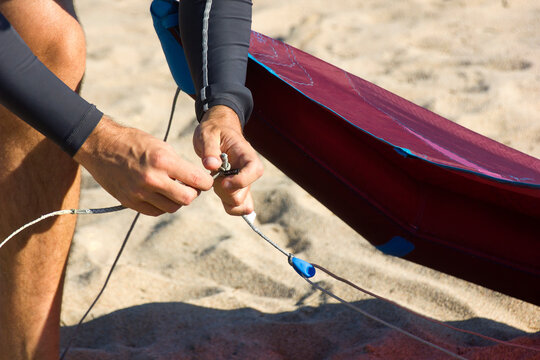 Kitesurfer on the beach preparing the equipment. male hands fixing kitesurf lines on a comet or kite before entering the sea. Kitesurfing equipment for kite courses. Extreme watersports. Wild lovers.