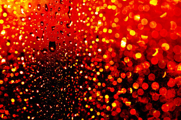 Rainy water drop through a window. glowing reddish particles.	