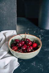 Fresh red sweet cherry in ceramic bowl on dark background.