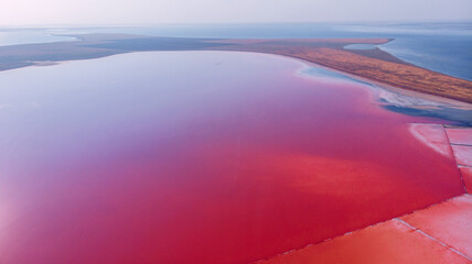 View from drone above the pink lake, sand spit and blue sea at distance.