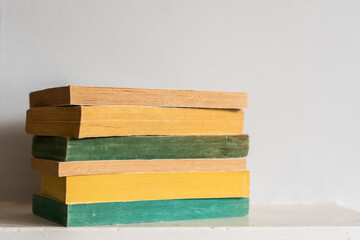 A stack of old paperback books with brightly coloured yellow and green pages