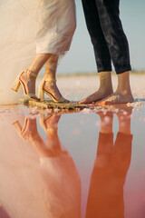 Reflection of newlyweds in water of the pink salty lake.