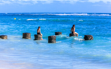 Enfants jouant sur des vestiges de piliers en mer, île de la Réunion 