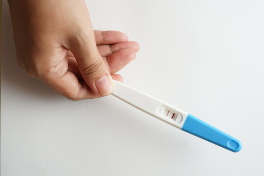 Pregnancy test pack hold by hand on top of white background.