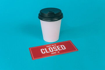Red plate Sorry We're Closed COVID-19 with a plastic cup of coffee.