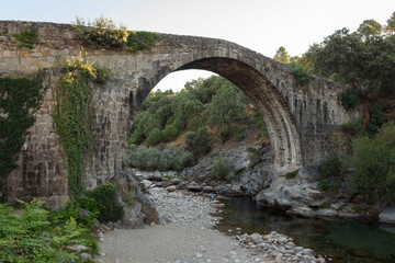 Fototapeta na wymiar Roman bridge in the Alardos gorge in Madrigal de la Vera, Caceres, Extremadura, Spain, Europe. Stone construction.