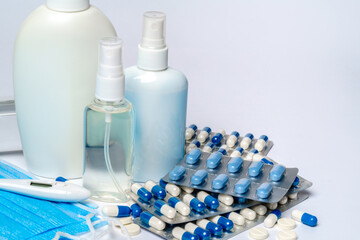 bottle of sanitizer or liquid soap, protective mask, medicine pills blisters and thermometer over...