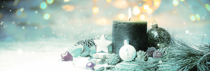 Christmas background - burning advent candle in the snow with bokeh lights in the background - winter banner - first advent
