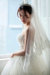 Asian women in white wedding dresses stand at the window waiting for the bridegroom's arrival, looking happy and happy