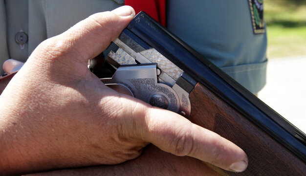 The hunter holds a two-barrel shotgun. Sports stelb on plates in the dash. Clay target shooter.