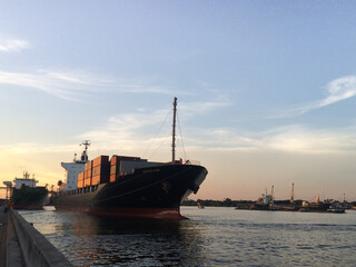 Fototapeta premium Cargo Ship Escort Cargo are Arrived at The Evening Sky