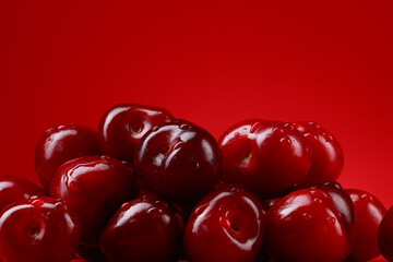 Drops of water on red ripe berries of a cherry.  Bunch of berries on a red background