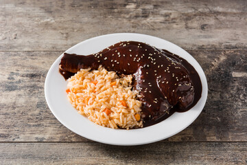 Traditional mole Poblano with rice in plate on wooden table
